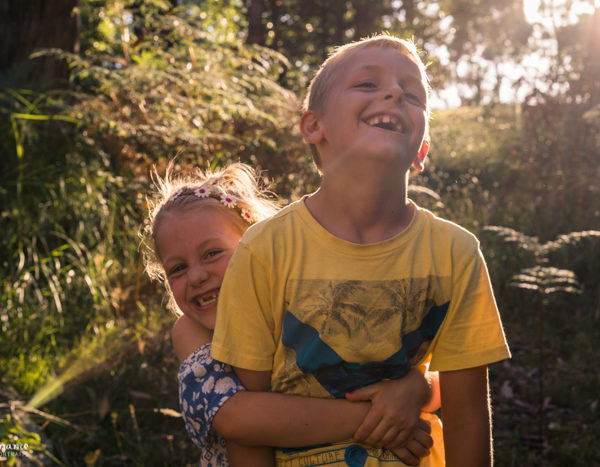 Lifestyle family portrait at Melbourne studio of siblings hugging in sunshine