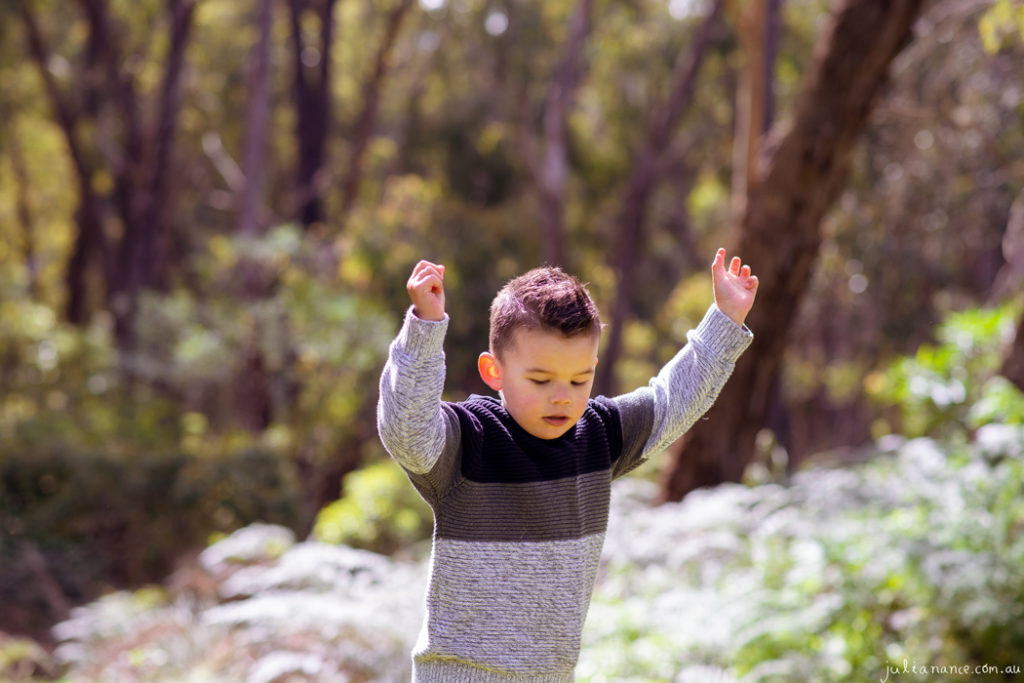 Boy explores bushland with hands in air at Melbourne family portrait studio